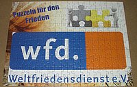 Ein Ausschnitt des Logos des Weltfriedensdienstes (wfd) auf einem Stoffstück.