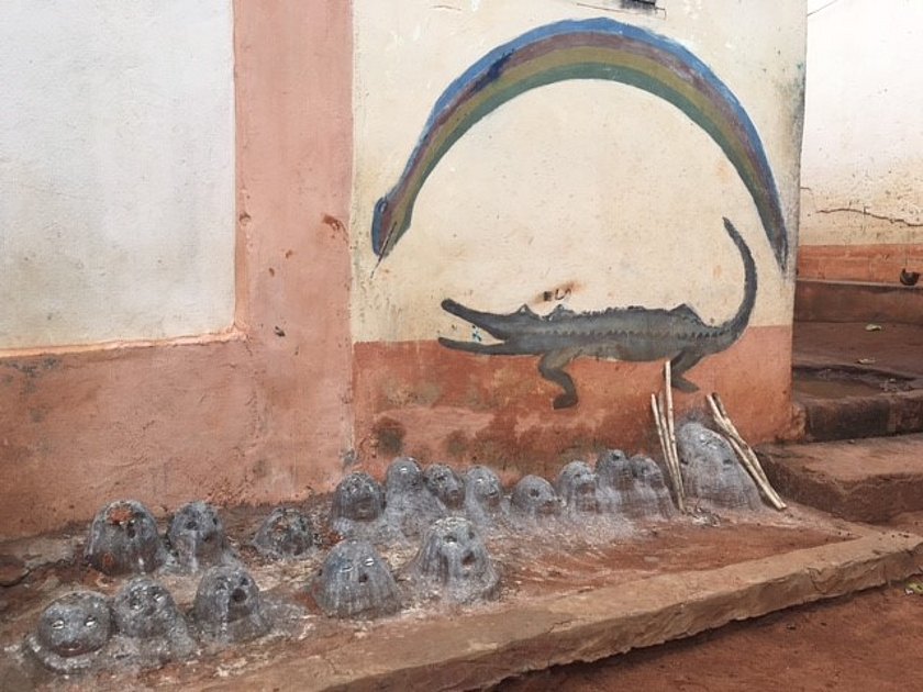 Eine handbetriebene Wasserpumpe, aus der Wasser in ein steinernes Auffangbecken fließt.