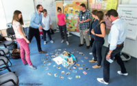 Gruppe von Menschen, die in einem Seminarraum zusammenstehen und an einer interaktiven Übung teilnehmen.